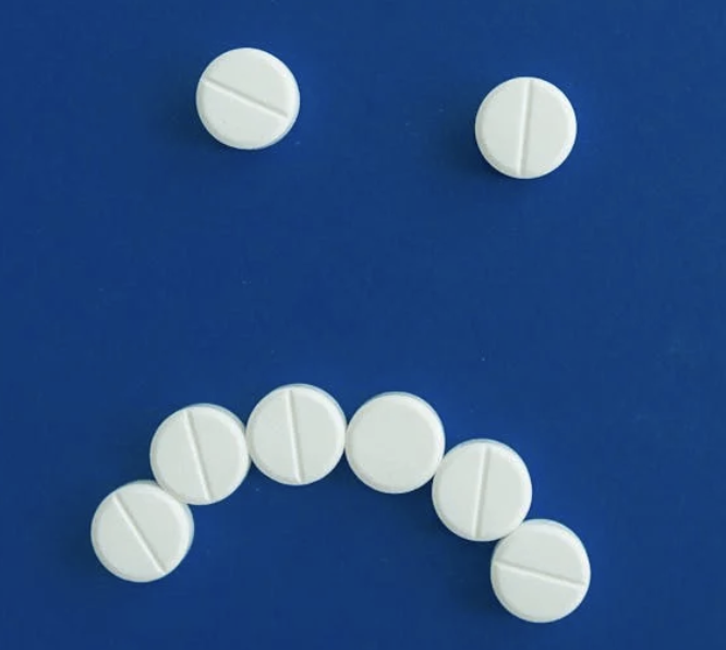 A bunch of pills lined up to look like a frowning face.